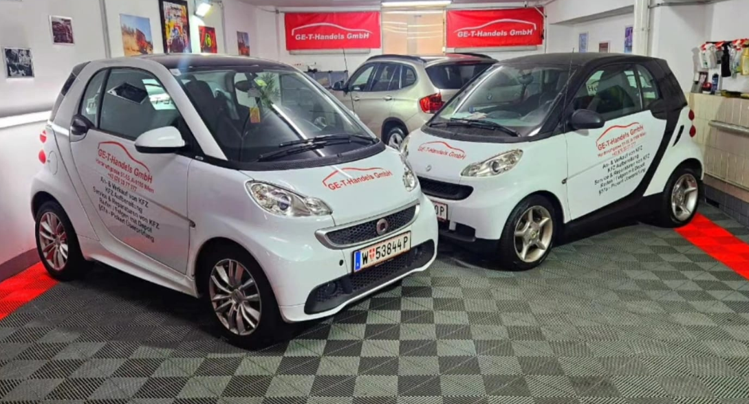 Zwei weiße Smart ForTwo mit Firmenbranding